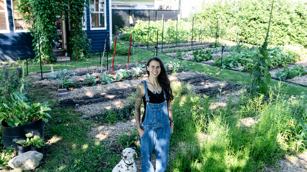 Candice standing in a garden next to her dog.