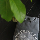 Cultivate the future sweatshirt folded on table with a plant