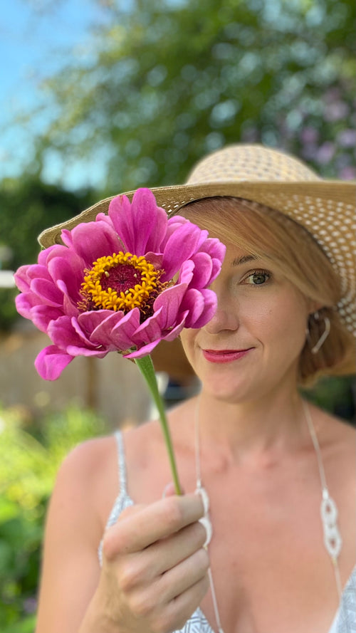 Erin holding a zinnia in front of half her face