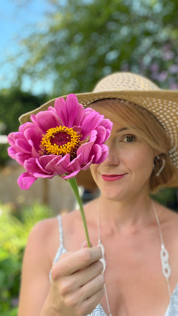Erin holding a zinnia in front of half her face